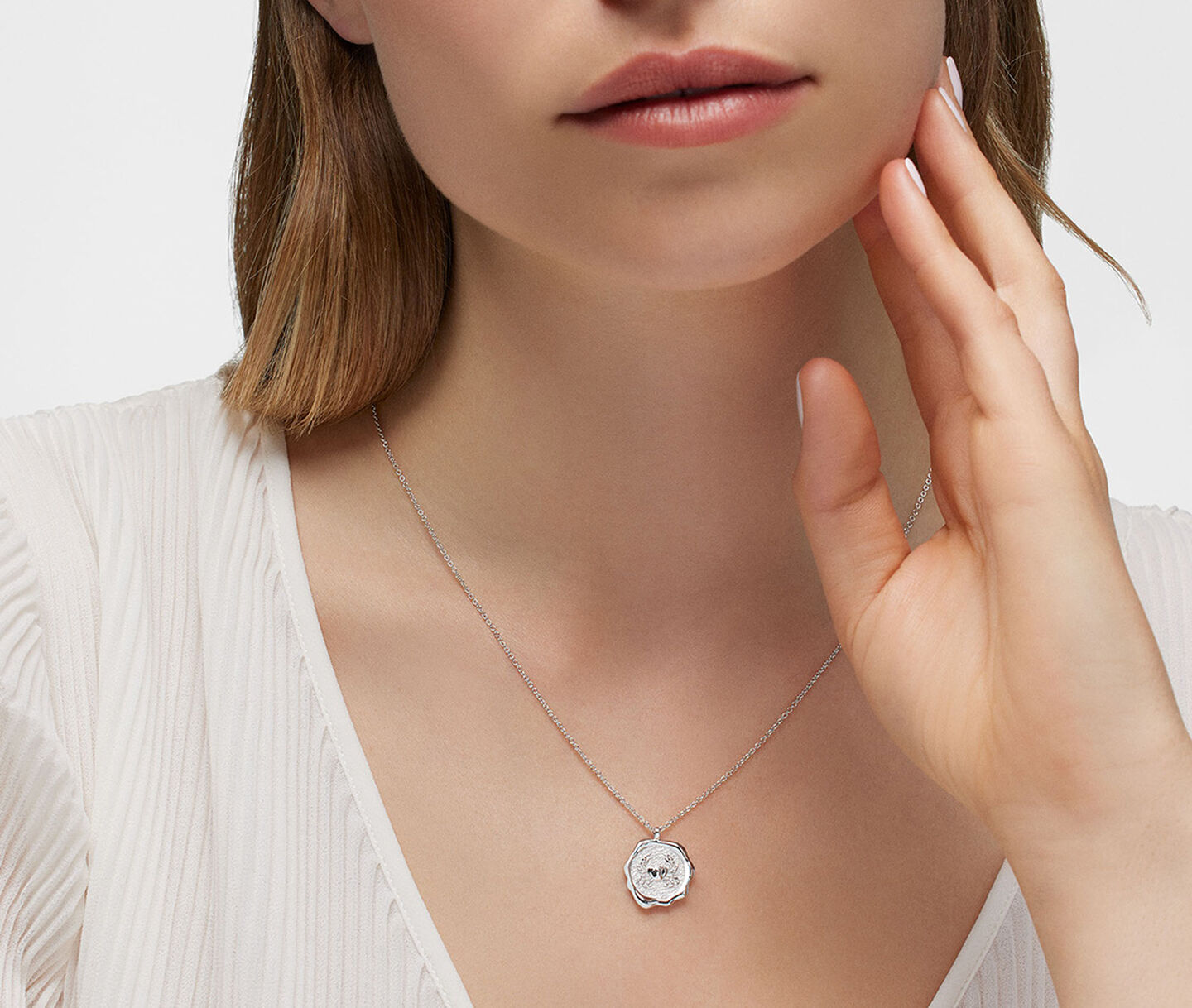 A woman wearing a Birks Zodiac silver necklace.